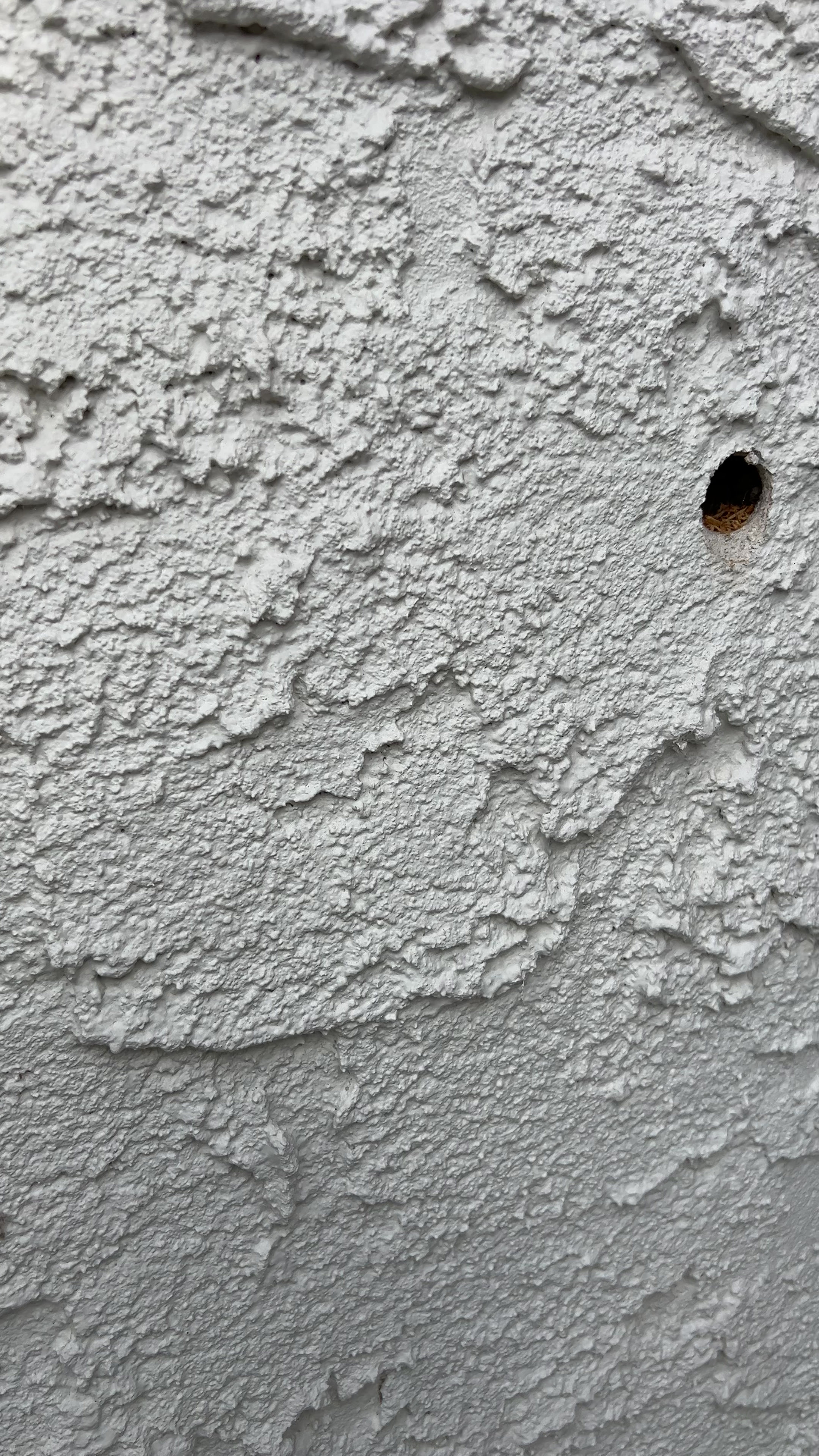 A closer view of a wall insulation opening in stucco.