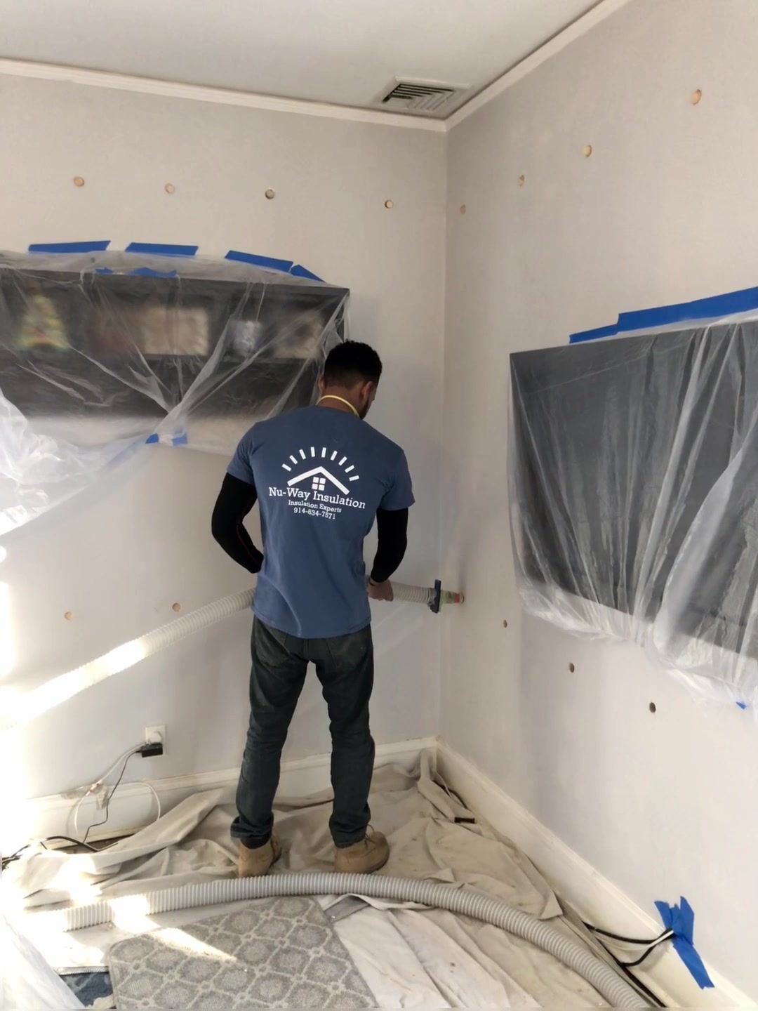 A Nu-Way installer works on wall cavities beside protected furnishings.